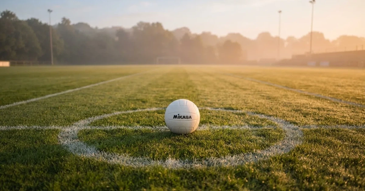 A ball on the centre spot of a grass pitch in morning light