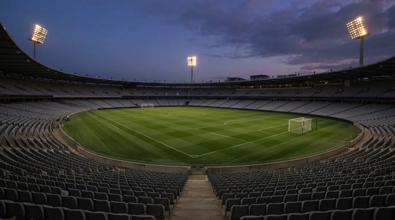 An empty football stadium with floodlight masts at dusk