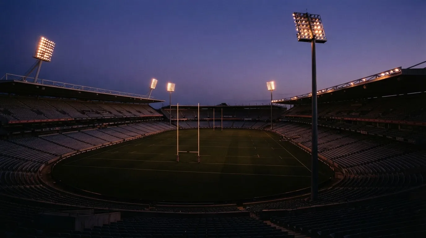 An empty football stadium with floodlight masts at dusk