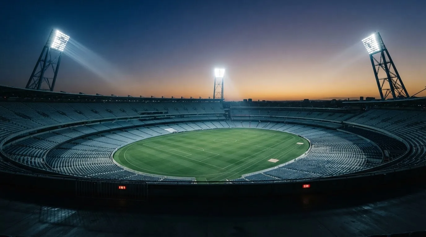 An empty football stadium with floodlight masts at dusk