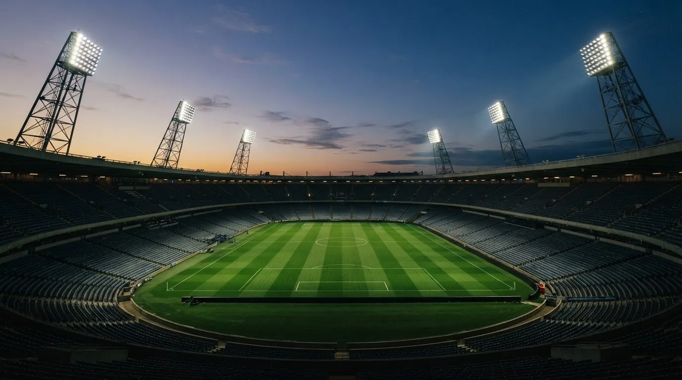 An empty football stadium with floodlight masts at dusk