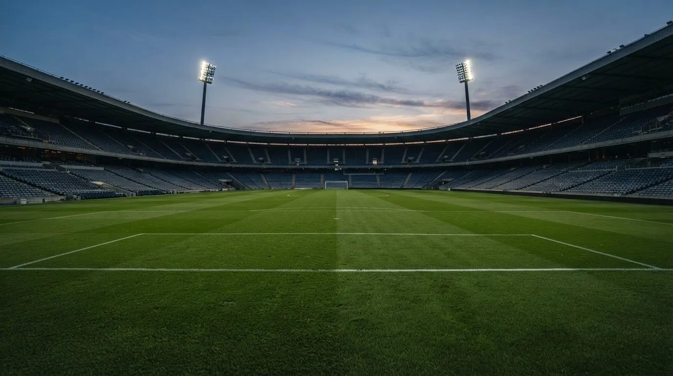 An empty football stadium with floodlight masts at dusk