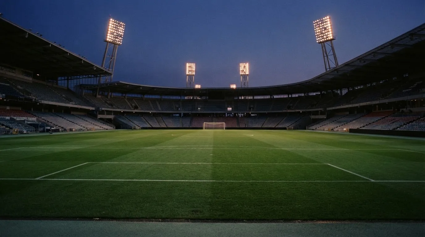 An empty football stadium with floodlight masts at dusk