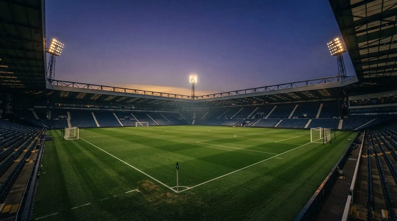 An empty football stadium with floodlight masts at dusk