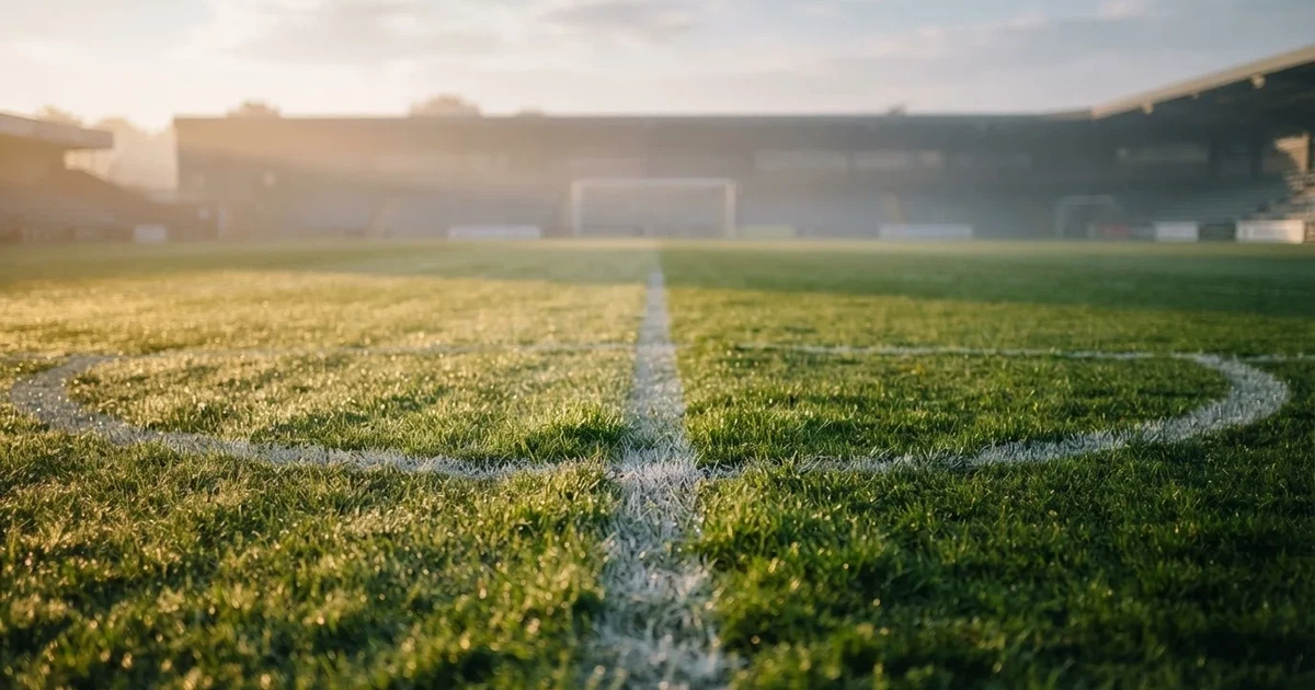 A ball on the centre spot of a grass pitch in morning light