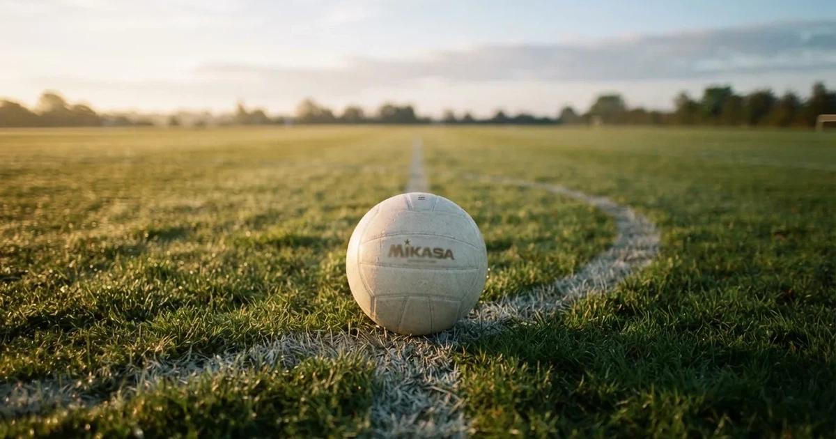 A ball on the centre spot of a grass pitch in morning light