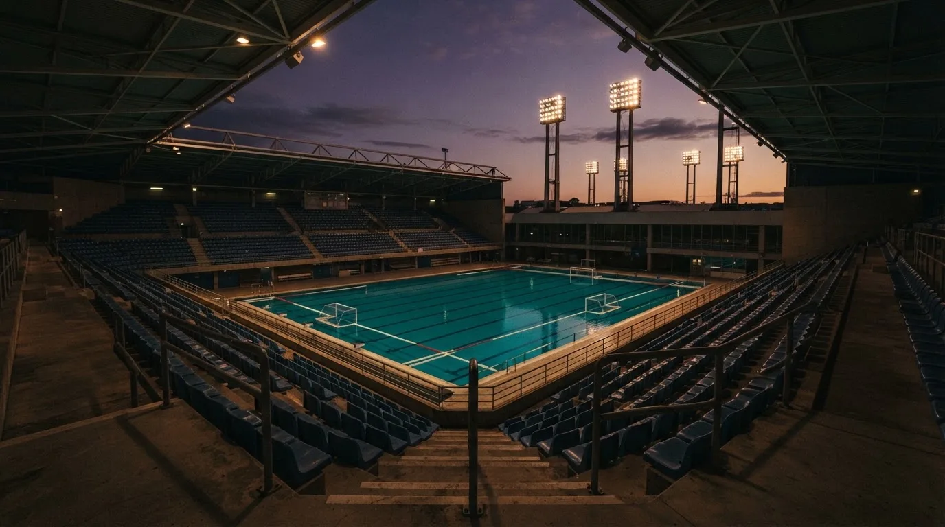 An empty football stadium with floodlight masts at dusk
