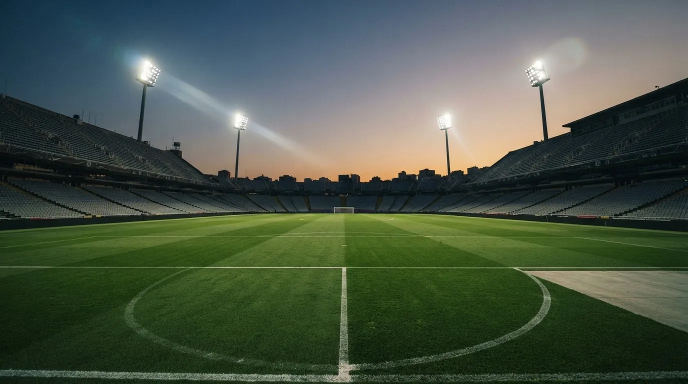 An empty football stadium with floodlight masts at dusk