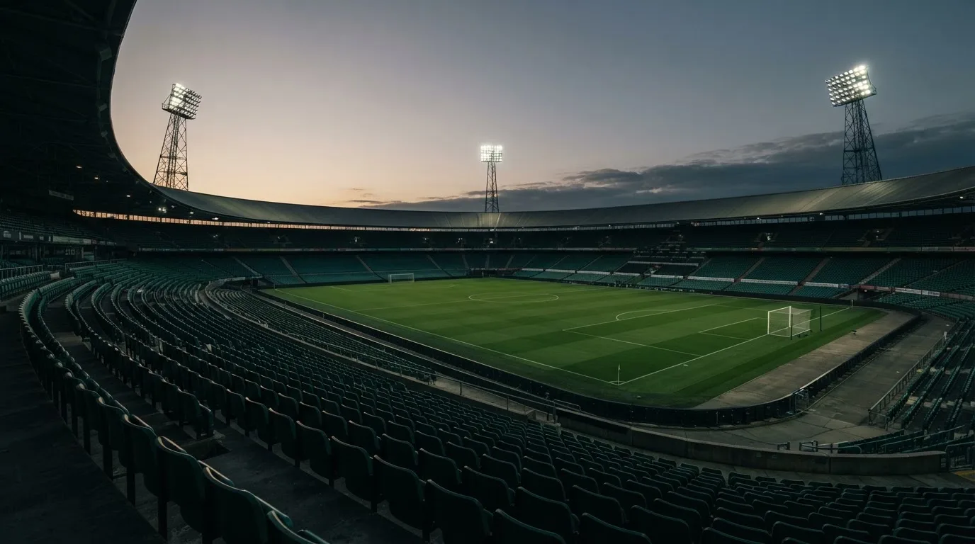 An empty football stadium with floodlight masts at dusk